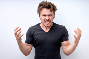 Yakışıklı adam izole edilmiş beyaz arka planda kızgın ve çılgın bir şekilde el kaldırıyor.