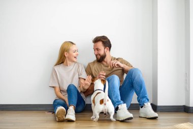 Evde köpeği olan genç bir çift, eğleniyorlar, birlikte vakit geçiriyorlar, yan gözle bakıyorlar.