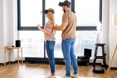 Kadın ve erkeğin yan görüşü. VR gözlükleriyle eğleniyorlar. Oynamayı öğreniyorlar.