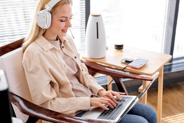 Evde çalışıyor, akıllı çalışıyor. Kadın dizüstü bilgisayar ve modern aygıtlar kullanıyor