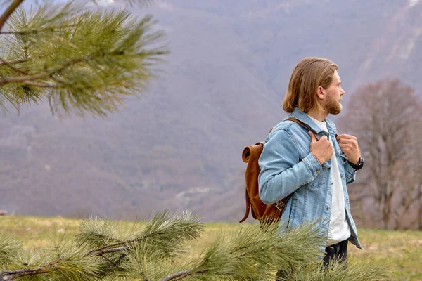 Jovem hipster pé sozinho ao ar livre com montanhas no fundo, andar — Fotografia de Stock