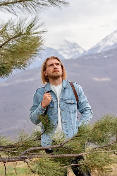 Netter kaukasischer Mann in Jeansjacke steht Seite an Seite in Betrachtung der Berge — Stockfoto