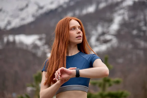 适合红头发的年轻女子侧视，锻炼时跑步后检查时间 — 图库照片