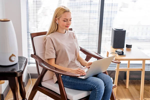 Erwachsene Frauen arbeiten am Laptop im Zimmer, mit drahtlosem Bluetooth-Lautsprecher und anderen Geräten — Stockfoto