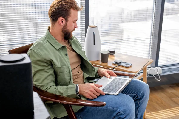 Zu Hause arbeiten, intelligent arbeiten. junger Mann benutzt Laptop und moderne Geräte zu Hause — Stockfoto