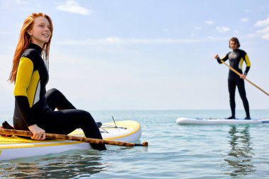 Güneşli bir günde, SUP 'de kürek çeken mutlu çift dinlensin.
