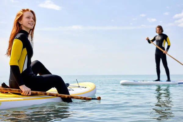 Casal feliz remando na placa SUP no mar no dia ensolarado, tenha descanso — Fotografia de Stock