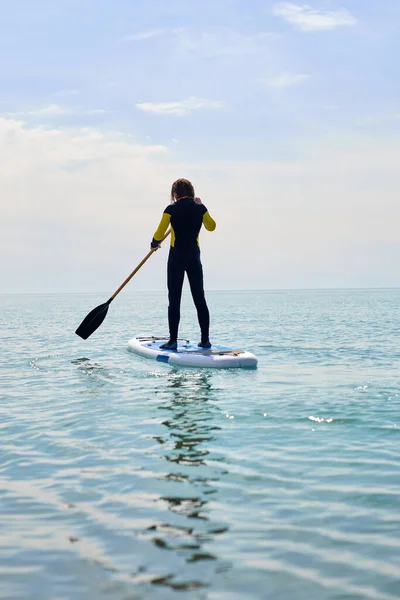 Deportista silueta de pie remando en la tabla de sup o tabla de surf, disfrutando del deporte —  Fotos de Stock