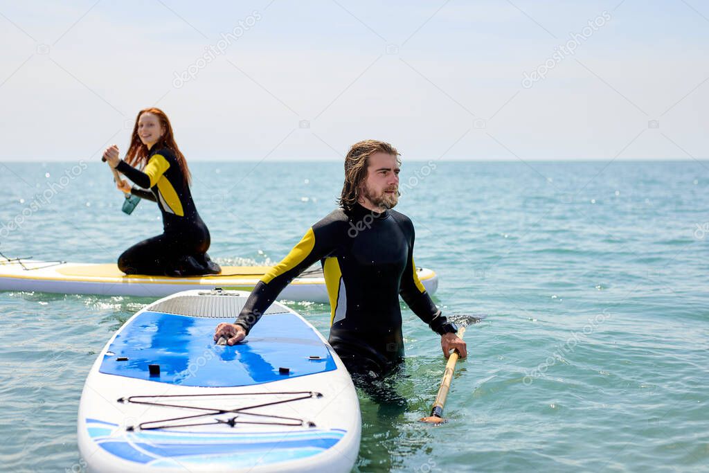 Paddle boarders. positive young man and woman on stand up paddleboard at sea