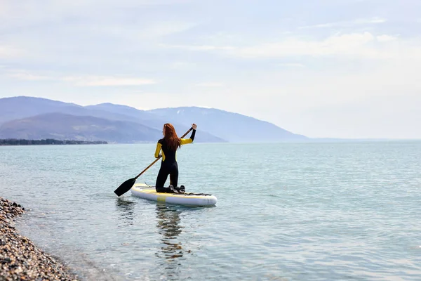 SUP Stand up paddle board. visão traseira na mulher jovem navegando em belo mar calmo — Fotografia de Stock