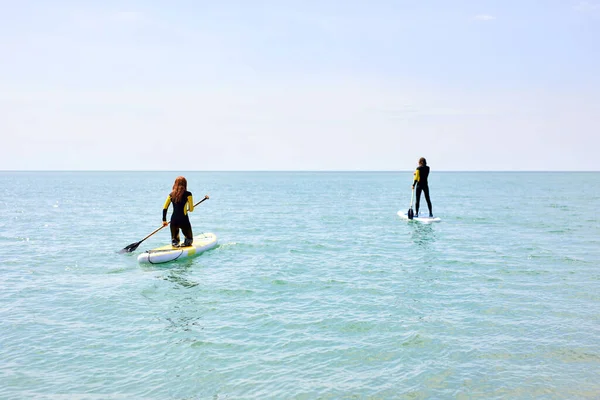 Mieszkańcy wioseł. młody mężczyzna i kobieta na stojąco paddleboard na morzu — Zdjęcie stockowe