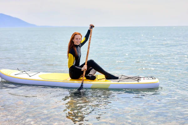 Surfista experiente do sexo feminino em SUP bordo no mar. Jovem mulher em pé paddleboard — Fotografia de Stock