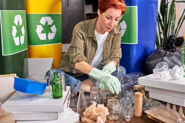 Woman sorting garbage. Redhead eco-friendly female separate waste and throwing trash