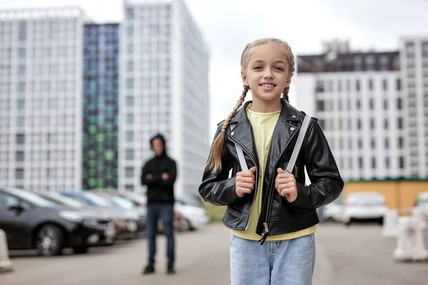 Blanc souriant enfant fille marche seul sur la rue, tandis que terrible maniaque la regardant — Photo
