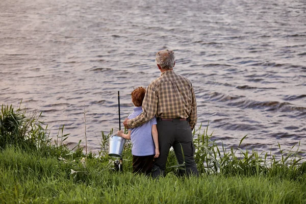 Nice multi-generation family fishing together from riverside at sunset