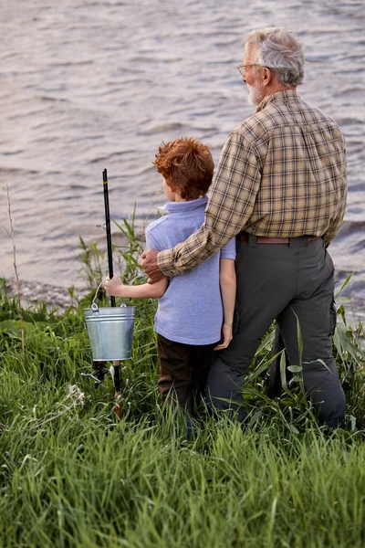 Pleasant multi-generation family fishing together from riverside at sunset — Stock Photo, Image
