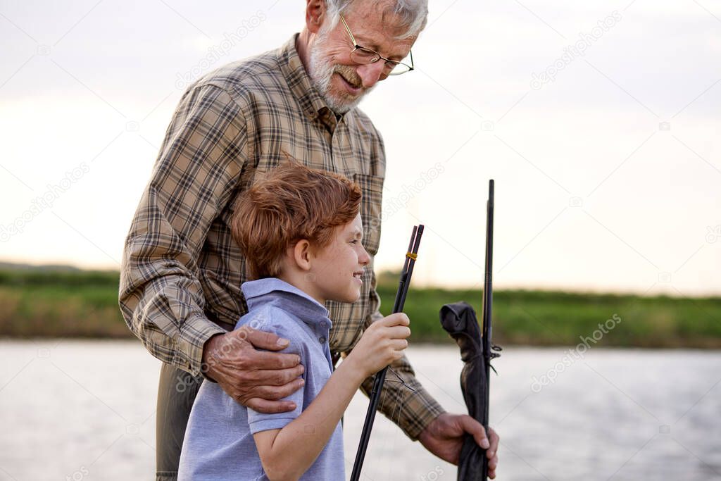 Anglers. Family bonding. Boy with grandfather fishing outdoor over river background