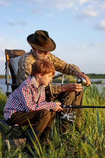 Nice homem sênior e menino envolvido na pesca juntos, no lago rural — Fotografia de Stock