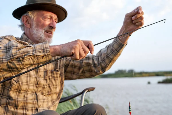 Homem idoso pescando no lago, pescando como hobby, retrato de vista lateral, no campo — Fotografia de Stock