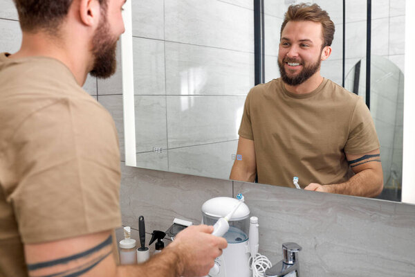 Male Person Brushing Teeth Using Electric Toothbrush, Close-up Photo Hands