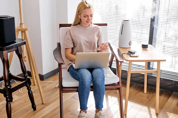 Работа дома, умная работа. блондинка с помощью ноутбука и более технологичных устройств — стоковое фото