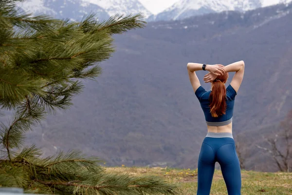 Rear view on sporty fitness woman stretching arms before workout training