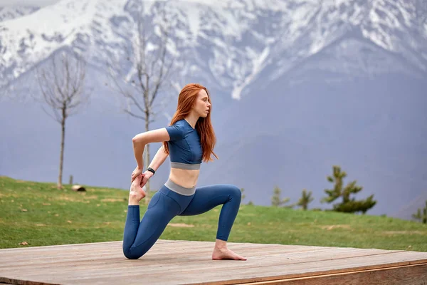 Side View Portret van flexibele blanke pasvorm vrouw stretching benen buiten — Stockfoto