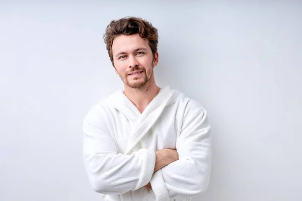 Bonito homem vestindo roupão sorrindo, posando com os braços dobrados, isolado em branco — Fotografia de Stock