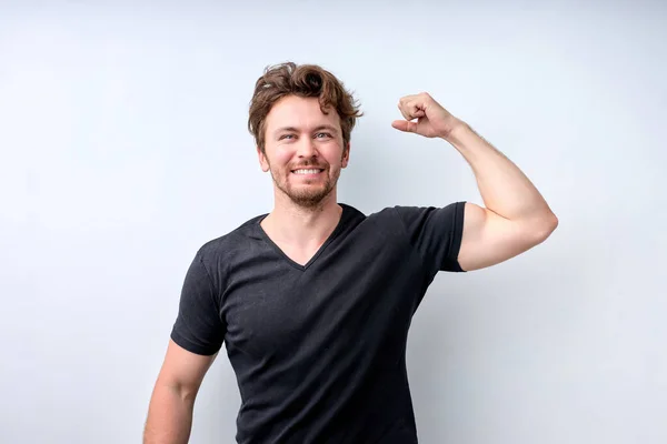 Positivo Forte jovem poderoso levanta os braços e mostra bíceps — Fotografia de Stock