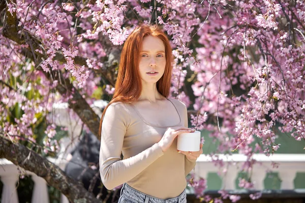 Gros plan portrait de jeune belle rousse femme mettant de la crème au parc de printemps — Photo