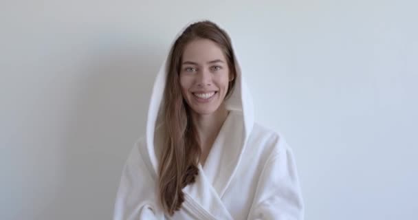 Гарна жінка в білому халаті посміхається на камеру, маючи ідеальну зубну посмішку — стокове відео