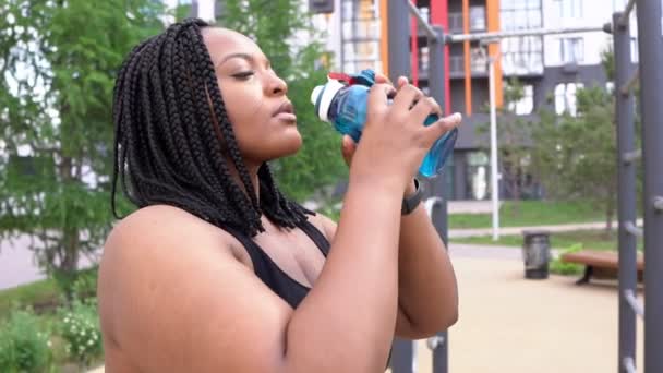 Overgewicht vrouw drinken water na joggen workout in de stad buiten — Stockvideo