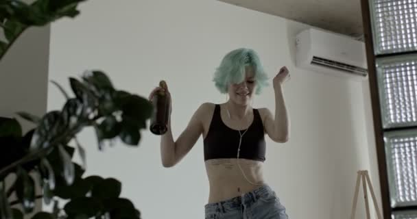 Depressieve en wanhopige vrouw die wijn drinkt en danst, in een koptelefoon, alleen — Stockvideo