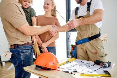 Genel çalışan üniformalı yakışıklı tamirci, anlaşmadan sonra müşterilerin ailelerine el sıkıştı