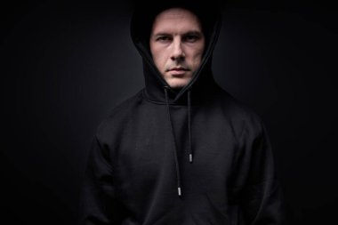 Siyah elbiseli bir erkek kameraya bakıyor, manyak ya da katil, siyah stüdyo arka planında izole edilmiş.