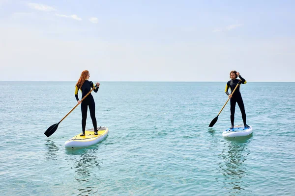 Mann und Frau paddeln auf hoher See. Junges Paar beim Wassersport — Stockfoto