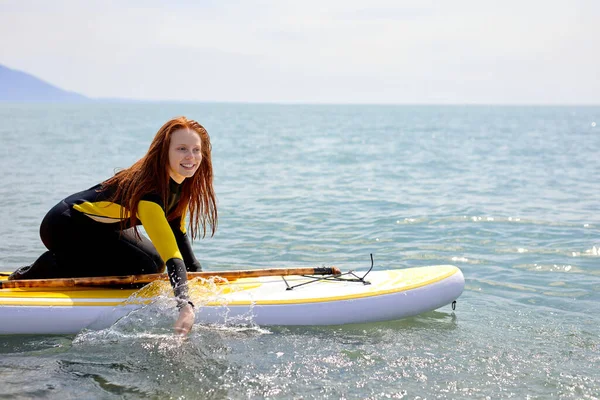 Young beuatiful redhead surfer woman making preparation for surf session — Fotografia de Stock