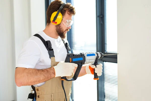 Uomo caucasico uso trapano elettrico sul muro nella nuova casa, Copia spazio, Miglioramento della casa — Foto Stock