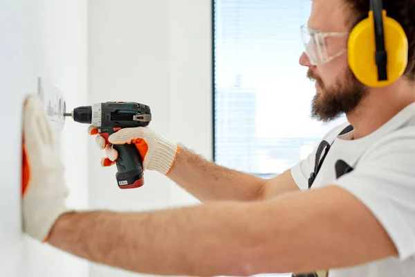 Side view portrait of confident electrician setting the outlet in room on white wall — Fotografia de Stock