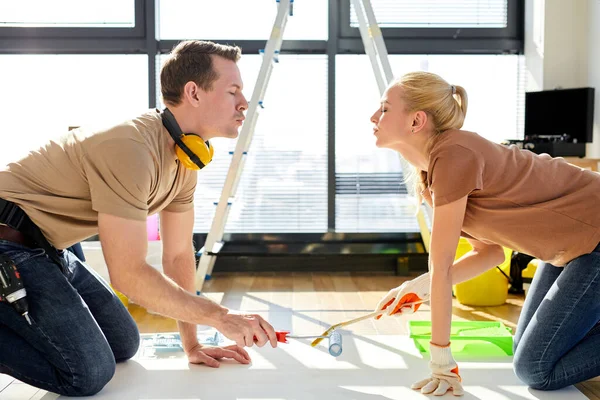 Portrait of cute married couple kissing each other, while painting on paper on floor — Fotografia de Stock