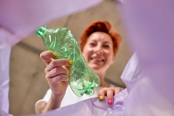 Woman throws plastic bottle in trash, bottom view. Plastic bottle is thrown away — Fotografia de Stock