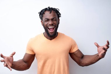 Heyecanlı genç Afrikalı adam kollarını açmış çığlık atıyor, siyah arka planda tecrit edilmiş.