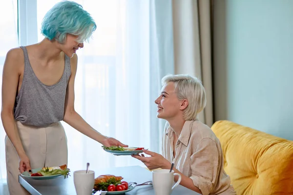 Vue latérale sur le couple de femmes de même sexe européen appréciant le petit déjeuner, parler et s'amuser — Photo