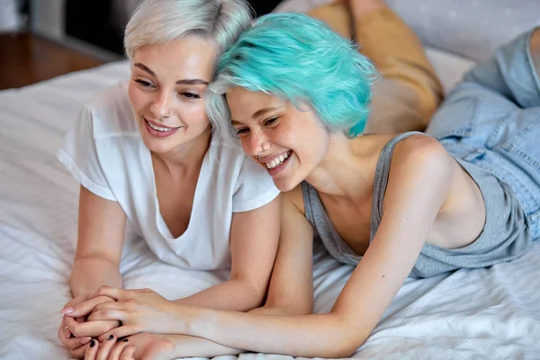 Cheerful beautiful lesbian or friends having talak, enjoying rest on bed at home. — Stockfoto