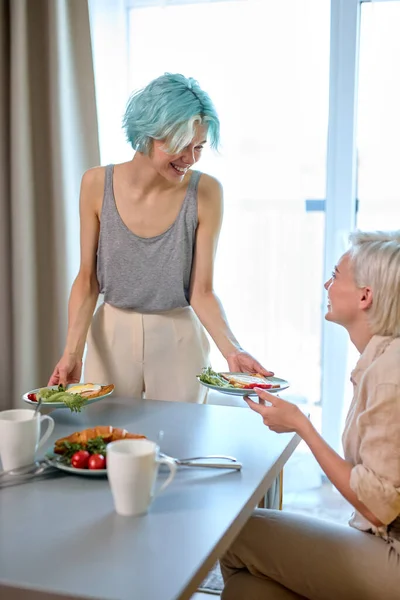 Excited caucasian lady lesbian treats girlfriend with breakfast, in the morning at home — Stock Fotó