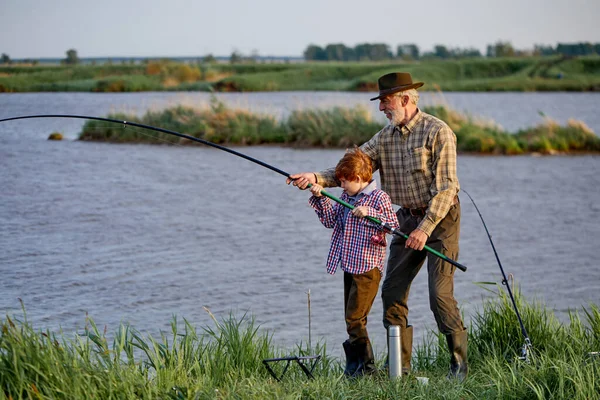 Caucásico jubilado pescador enseñanza lindo nietos pesca en el lago en la naturaleza — Foto de Stock