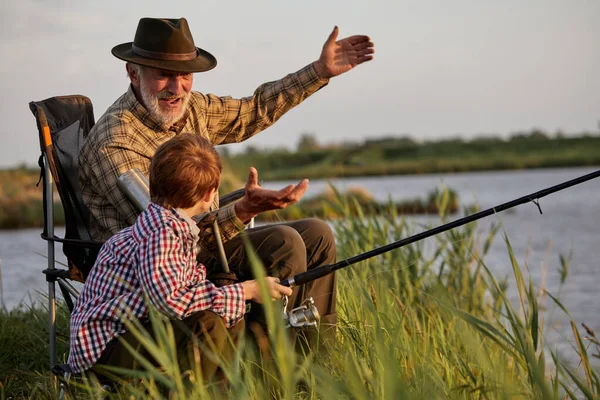 Granddad and kid boy together fishing in the evening at sunset time in summer day — Fotografia de Stock