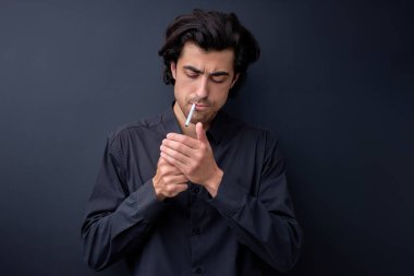 Sigara içen yakışıklı, siyah arka planda izole bir adam.
