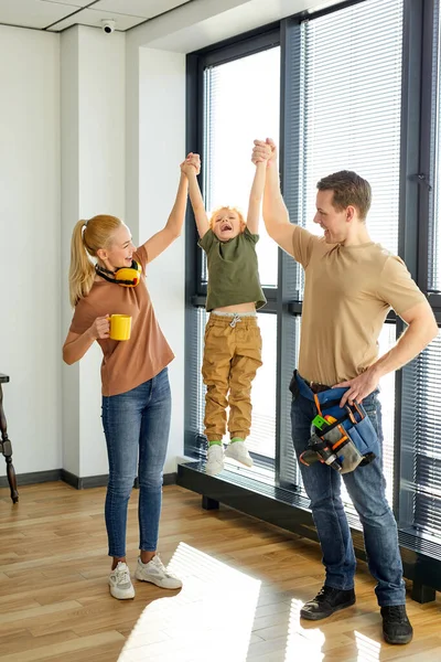 Familia alegre con niño diviértete en apartamento nuevo, disfruta de casa reformada terminada —  Fotos de Stock