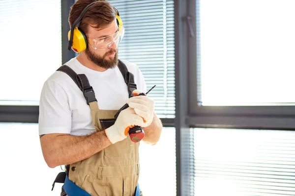 Focused Handyman In Safety Glasses and Overall, Hold Electric Power Tool In Hands — Fotografia de Stock